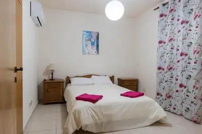 a bedroom with a bed with pink towels on it at EURO CARISSA FLAT 101 in Larnaka