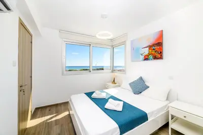 a white bedroom with a bed and two windows at Infinity View Villa in Ayia Napa