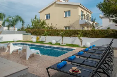 a row of lounge chairs next to a swimming pool at Villa Fortuna in Ayia Napa