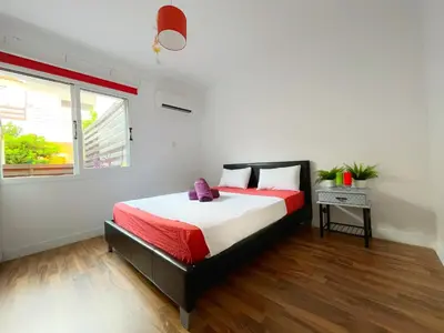 a bedroom with a bed with a red and white comforter at Central 2 Bedroom Apt Terrace and Pool in Ayia Napa