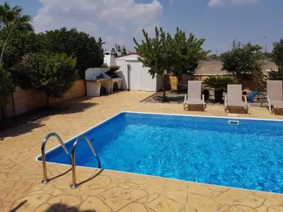 a swimming pool with chairs next to a house at Sunrise Villa in Ayia Napa