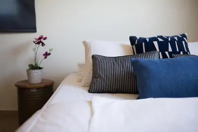 a white bed with blue pillows and a plant on a table at Penthouse Duplex overlooking the Mediterranean in Larnaka
