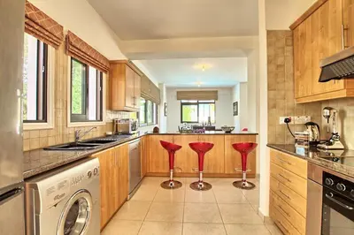 a kitchen with a washer and dryer and two red stools at Villa Anatoli - Cape Greco in Protaras