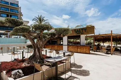 a patio with tables and chairs in front of a restaurant at Cavo Zoe Seaside Hotel in Protaras