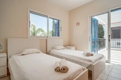 two beds in a room with two windows at Amphitrite Villa in Paralimni
