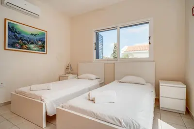 two beds in a room with a window at Amphitrite Villa in Paralimni