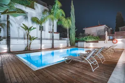 a swimming pool with chairs on a deck at night at Amphitrite Villa in Paralimni