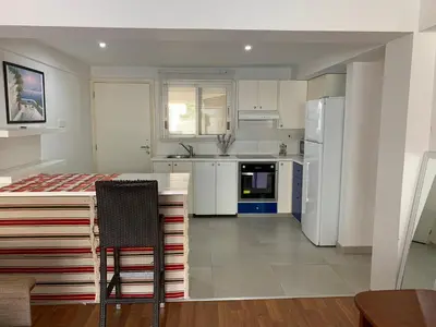 a kitchen with white appliances and a table and chairs at Napa Blue Apartment, XXL Pool,in Hearth of Ayia Napa in Ayia Napa