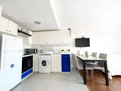 a kitchen with a table and a washing machine at Napa Blue Apartment, XXL Pool,in Hearth of Ayia Napa in Ayia Napa