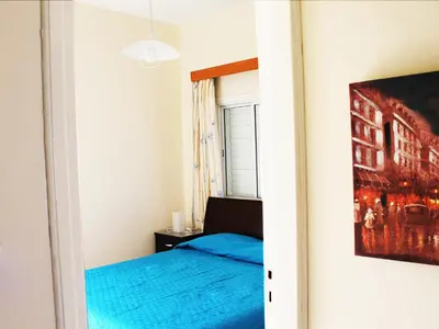 a bedroom with a blue bed and a painting on the wall at Panorama Beach House, 5 meters to the sea in Pervolia