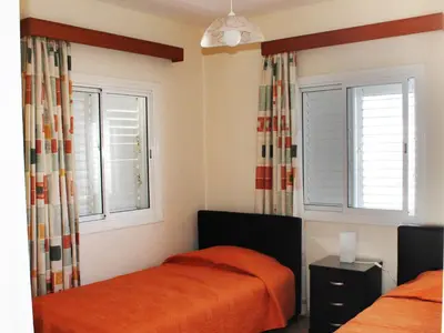 a bedroom with two beds and two windows at Panorama Beach House, 5 meters to the sea in Pervolia
