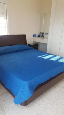 a bed with a blue comforter in a bedroom at Panorama Beach House, 5 meters to the sea in Pervolia