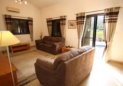 a living room with a couch and a table and windows at Pissouri Bay Bungalow in Pissouri