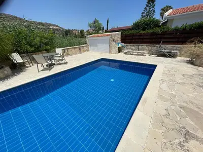 a blue swimming pool in a yard with a house at Pissouri Bay Bungalow in Pissouri
