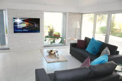 a living room with a couch and a tv on a wall at Maria Zintili Apartments in Ayia Napa