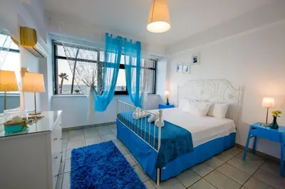a blue and white bedroom with a bed and a window at Krasas Beach Apts in Larnaka
