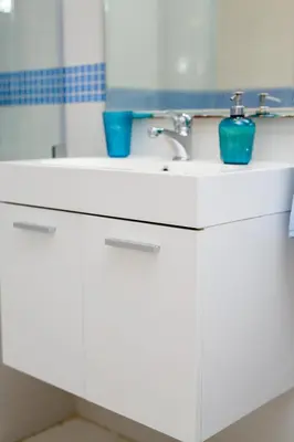 a white bathroom sink with two blue cups on it at Krasas Beach Apts in Larnaka