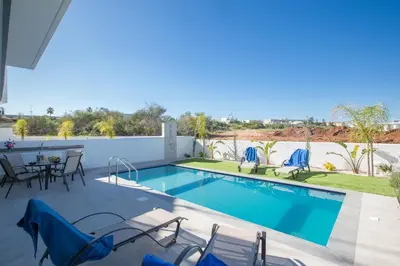 a swimming pool with chairs and a table on a patio at Oli Vine Villas in Protaras