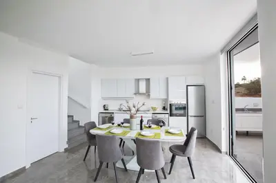 a white kitchen and dining room with a table and chairs at Oli Vine Villas in Protaras