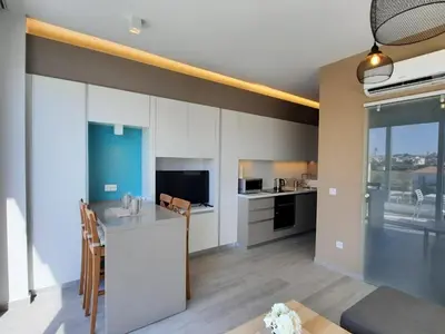 a kitchen and living room with white cabinets at Mythical Resort by KARMA in Paralimni