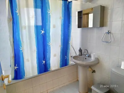 a bathroom with a sink and a blue shower curtain at Constantaras Apartments in Protaras