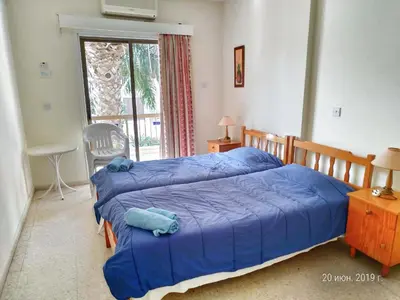 a bedroom with a bed with blue sheets and a window at Constantaras Apartments in Protaras