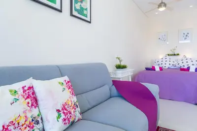 a living room with a blue couch with colorful pillows at Carmencita Studio B14 with pool in Limassol