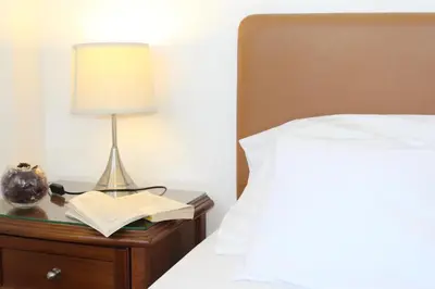 a bedside table with a lamp and an open book at Natali villa in a perfect location in Paralimni