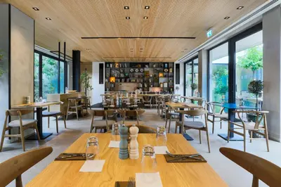 a restaurant with wooden ceilings and tables and chairs at Hotel Indigo Larnaca by IHG-ADULTS ONLY in Larnaka