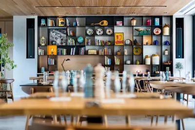 a restaurant with tables and chairs and bookshelves at Hotel Indigo Larnaca by IHG-ADULTS ONLY in Larnaka
