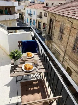 a table with plates of food on a balcony at Cozy place in Larnaka