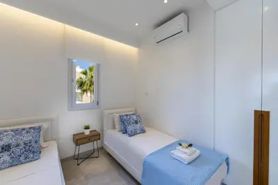 a white bedroom with a bed and a window at Mackenzie Castella Beachfront Suite in Larnaka
