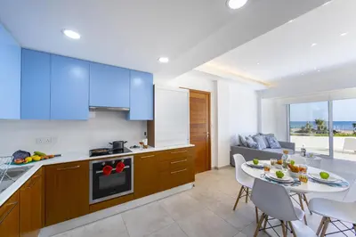 a kitchen and dining room with a table and chairs at Mackenzie Castella Beachfront Suite in Larnaka