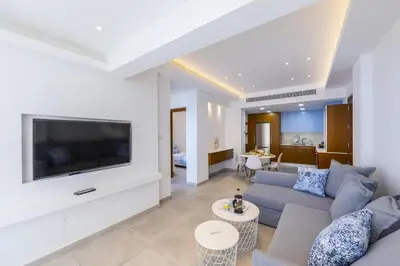 a living room with a couch and a tv at Mackenzie Castella Beachfront Suite in Larnaka