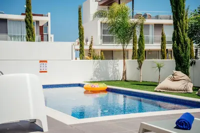 a swimming pool with an inflatable raft in front of a building at Protaras Olivia Pearl Villa in Paralimni