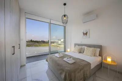 a bedroom with a large bed and a large window at Protaras Olivine Pearl in Protaras