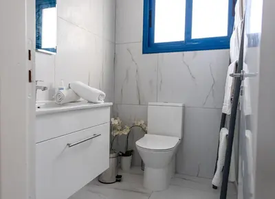 a white bathroom with a toilet and a window at Protaras Villa Nicol 21 in Paralimni