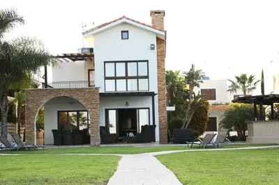 a white house with chairs in a yard at Ionion Beachfront Villa in Ayia Napa