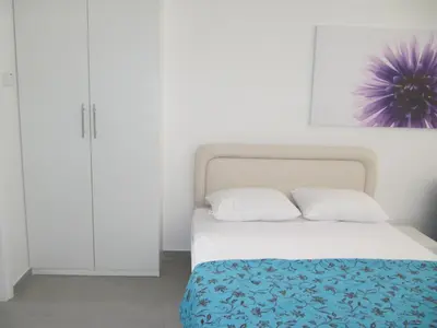 a white bedroom with a bed and white cabinets at Sunny Holiday Apartments in Protaras