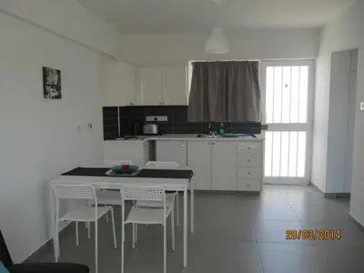 a white kitchen with a white table and chairs at Sunny Holiday Apartments in Protaras