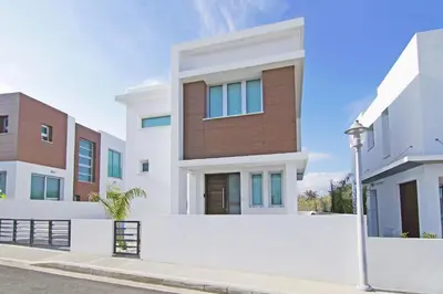 a modern house with white walls and a fence at Villa Caren in Paralimni