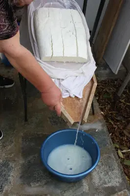 a person is pouring milk into a bowl of water at Aperanti Agrotourism in Pera Orinis