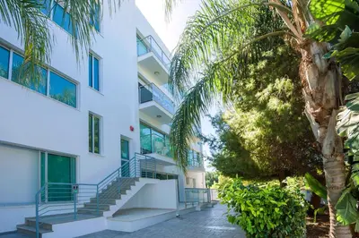 an apartment building with stairs and a palm tree at Lucile - Coralli Beachfront Apartment in Paralimni