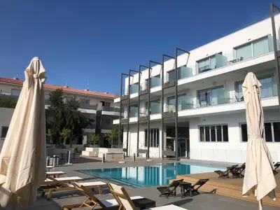 a hotel with a swimming pool and two umbrellas at Mythical Sands Resort - Maria in Protaras