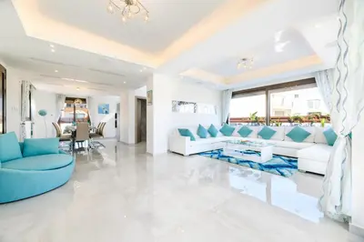 a living room with white furniture and a blue couch at Serenity Seafront Villa in Ayia Napa