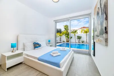 a bedroom with a bed and a view of a pool at Blue Pelagos Villa in Protaras