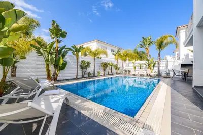 a swimming pool with chairs next to a house at Blue Pelagos Villa in Protaras