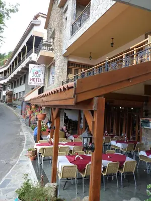 a restaurant with tables and chairs in front of a building at Mountain Rose Hotel & Restaurant in Pedoulas
