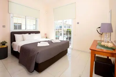a bedroom with a bed and a table and windows at Villa Oceania - Beachfront in Paralimni