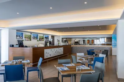 a restaurant with tables and chairs and a bar at Tofinis Hotel in Ayia Napa